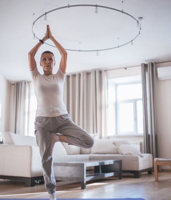 Person stretching gently on a yoga mat in a bright room.